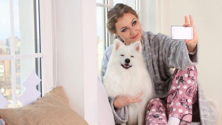 woman holding a white dog on the bed