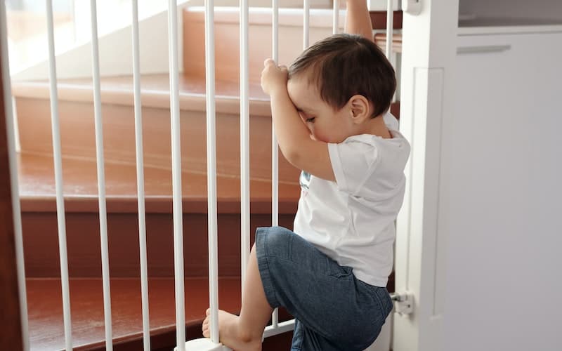 child holding on to a baby gate